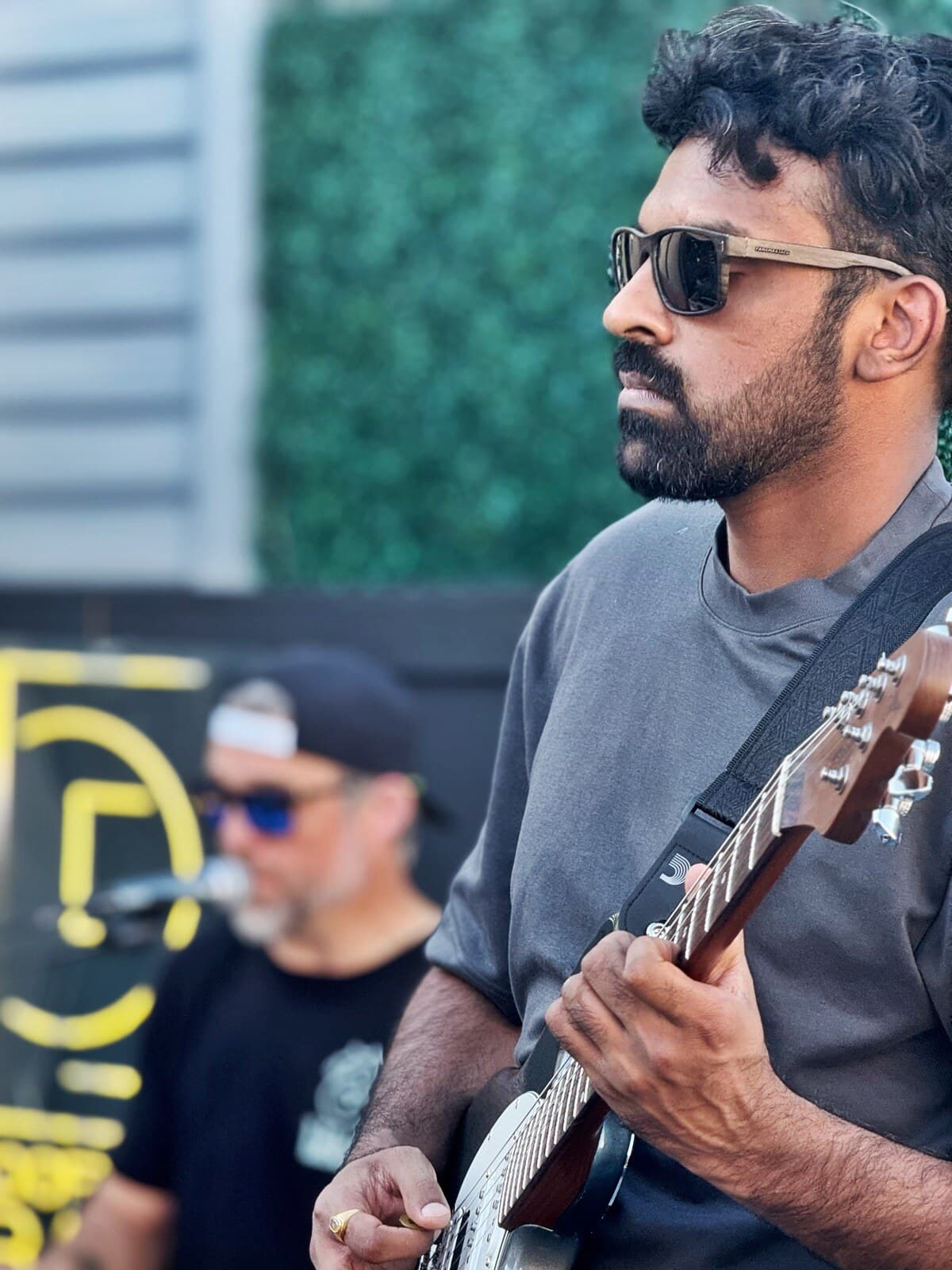 Krishna Peri playing guitar outdoors at a gig